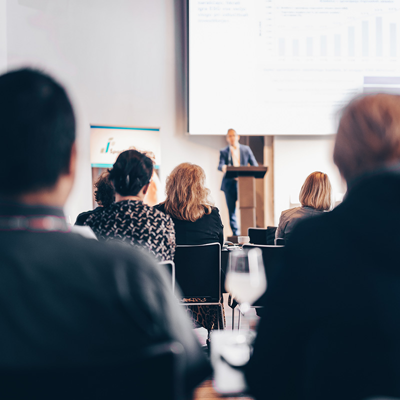 Man talking behind a podium in a conference room. 